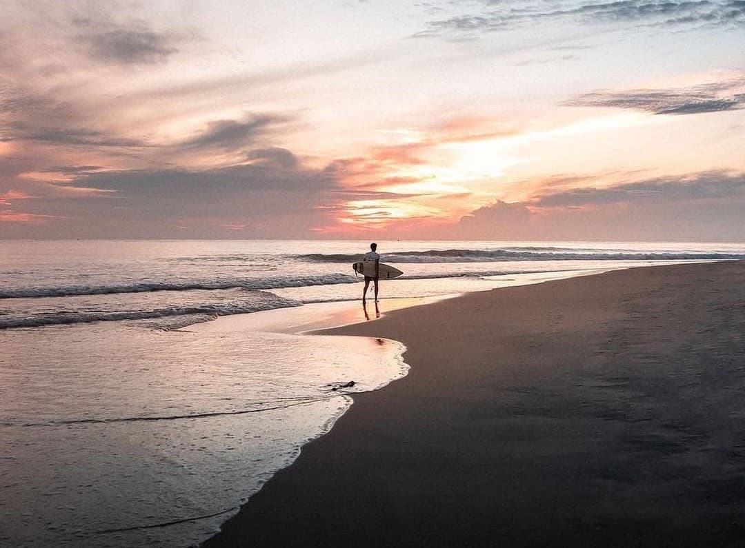Perfect surf break at Arugam Bay with surfers riding waves, palm trees, and golden beach