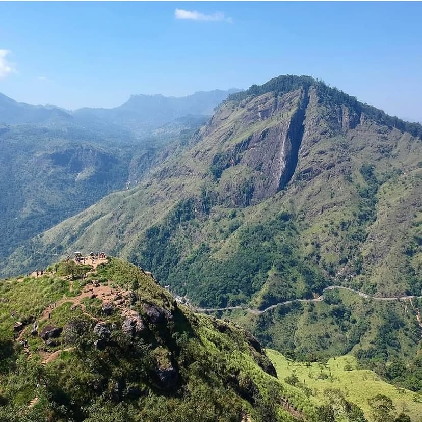 Adventurous hikers on Ella Rock summit with dramatic mountain landscape and tea estates below