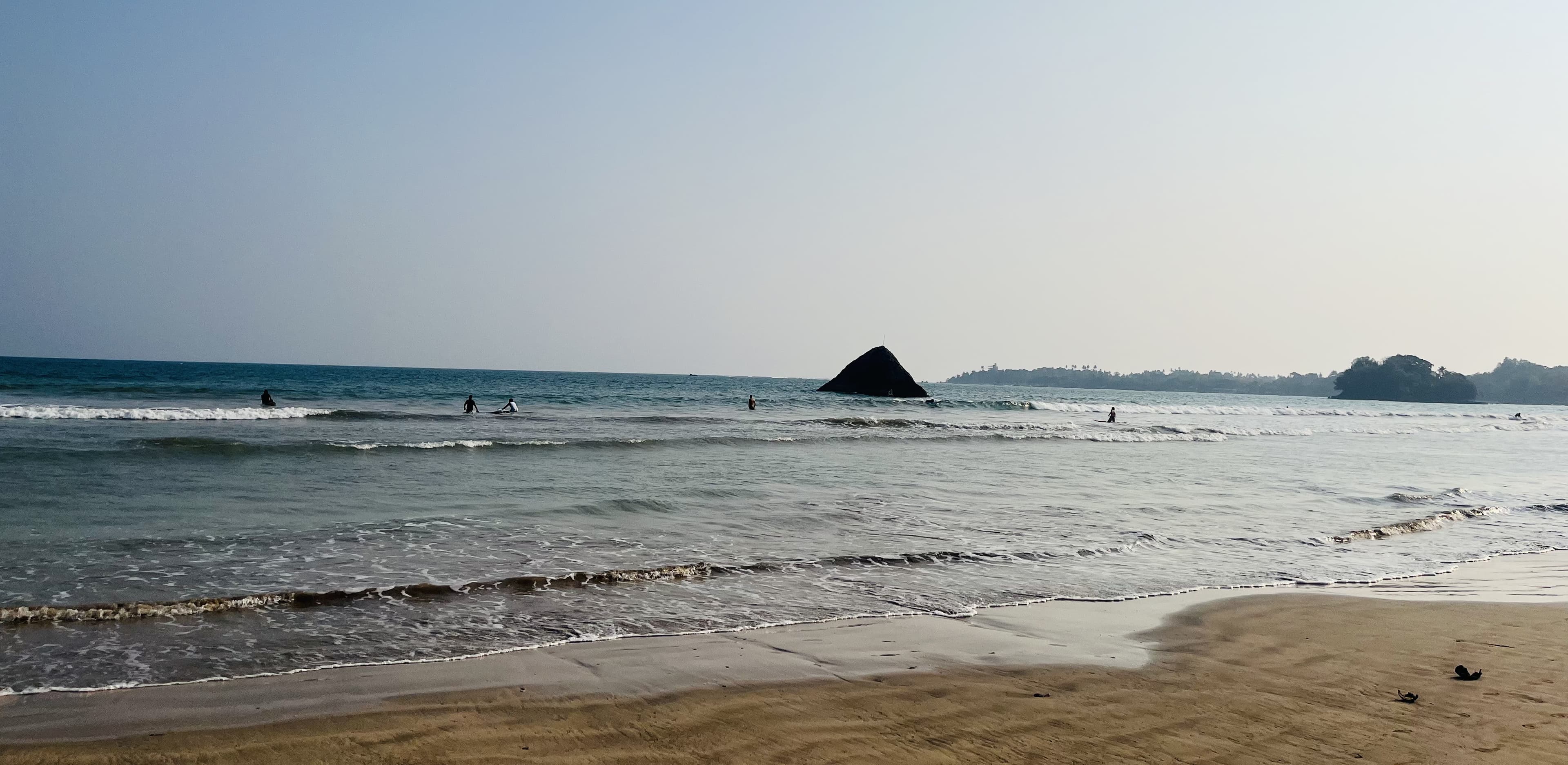 Stunning view of Weligama Bay showing traditional stilt fishermen on wooden poles, golden sand beaches, and tropical coastline