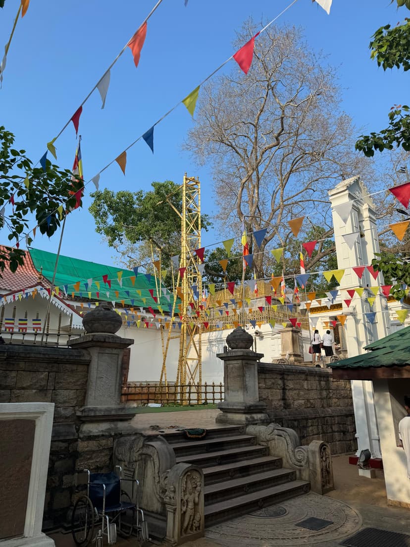 Sacred Sri Maha Bodhi tree in Anuradhapura with pilgrims offering prayers and white flags