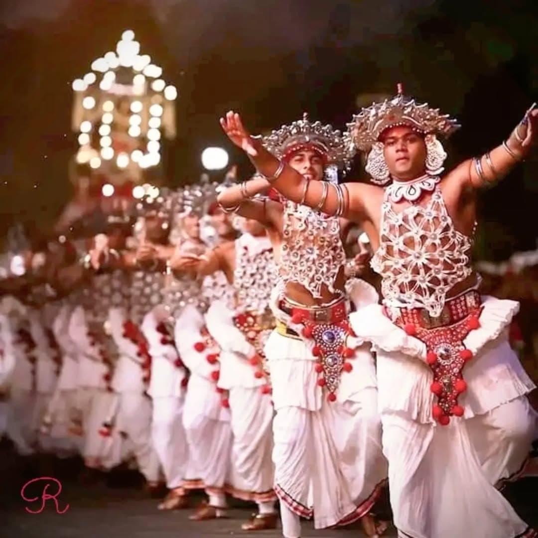 Kandyan dancers in elaborate traditional costumes with silver decorations and colorful silk cloths performing graceful movements