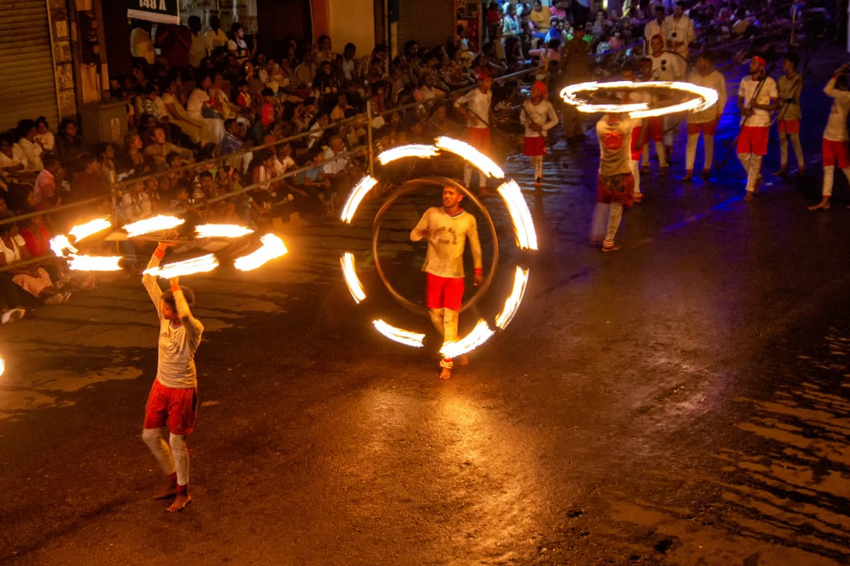 Fire dancers creating spectacular displays with flames while traditional drummers play ancient rhythms during the night procession